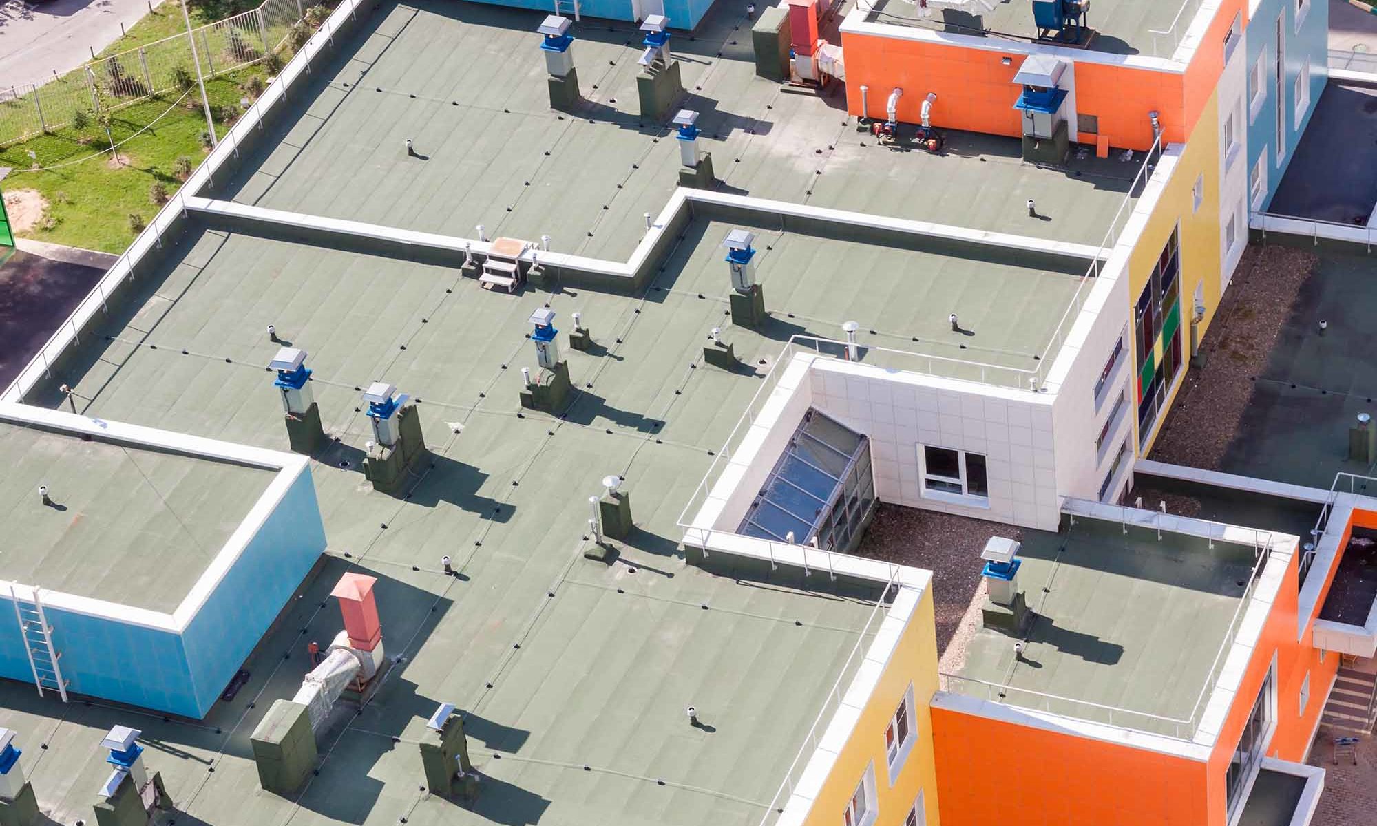Top view flat roof with air conditioners and hydro insulation membranes on top of a modern blue and orange apartment